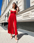 Rochie rosie midi elegantă cu decupaj frontal și bretele subțiri.