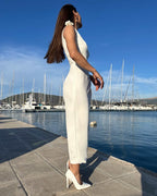 Rochie alba petrecere fără mâneci cu slit elegant și detalii florale, purtată la eveniment în aer liber.