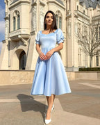 Rochie eleganta de ocazie albastra cu croială A-line, design rafinat, fundal arhitectural.