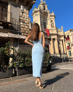 Rochie eleganta albastra cu decolteu și slit, purtată de o femeie în fața unei clădiri istorice.