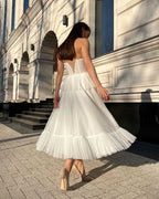 Rochie alba midi cu corset dantelă și șiret reglabil, perfectă pentru evenimente speciale.