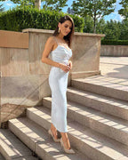 Rochie satin din satin regal cu tăietura sofisticată și pliuri, purtată de model pe trepte exterioare.