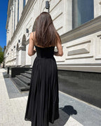 Rochie neagra cu slit și bretele, vedere spate, pe un drum urban.